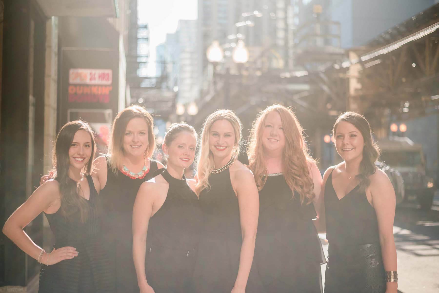 Six female friends standing together smiling on a bachelorette trip in Chicago, USA