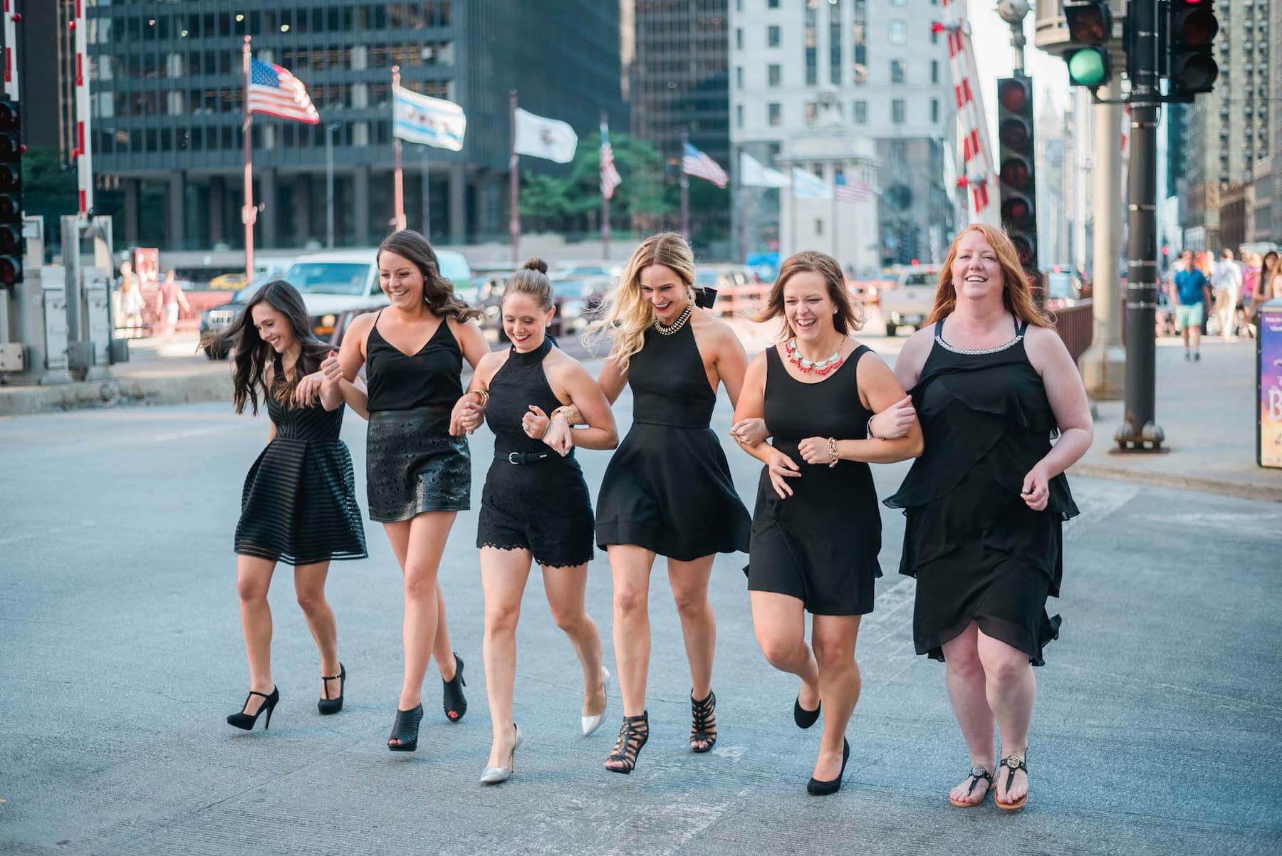 Six female friends crossing the street and holding hands on a bachelorette trip in Chicago, USA