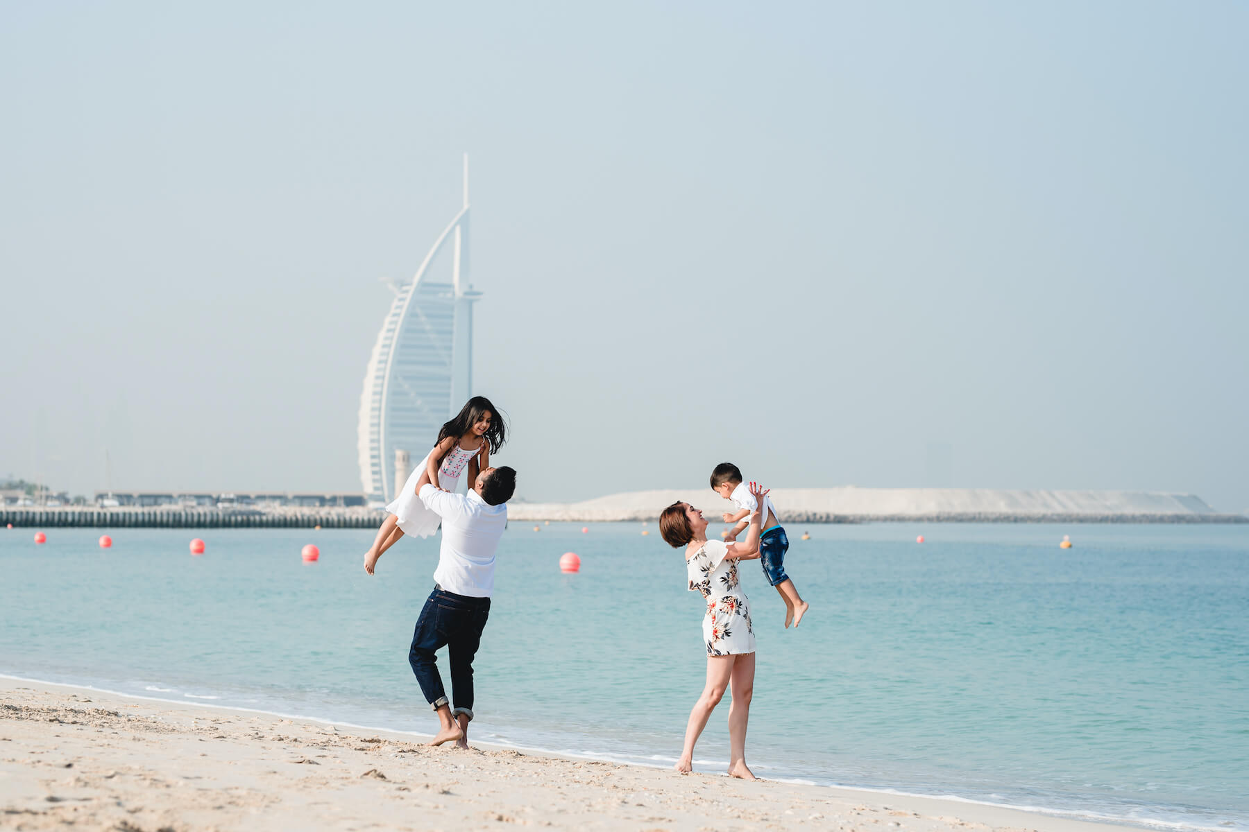 Couple standing together on a boardwalk with Jumeirah Beach Hotel in the background in Dubai