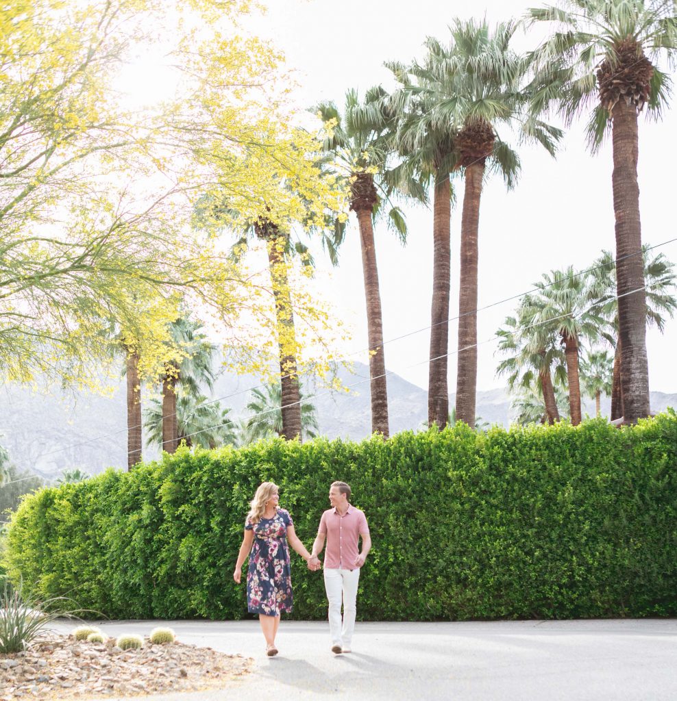 A man and woman walk hand in hand in Palm Springs