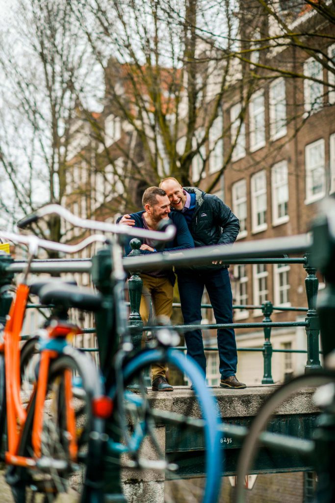 Two men laugh and hug on a canal in Amsterdam