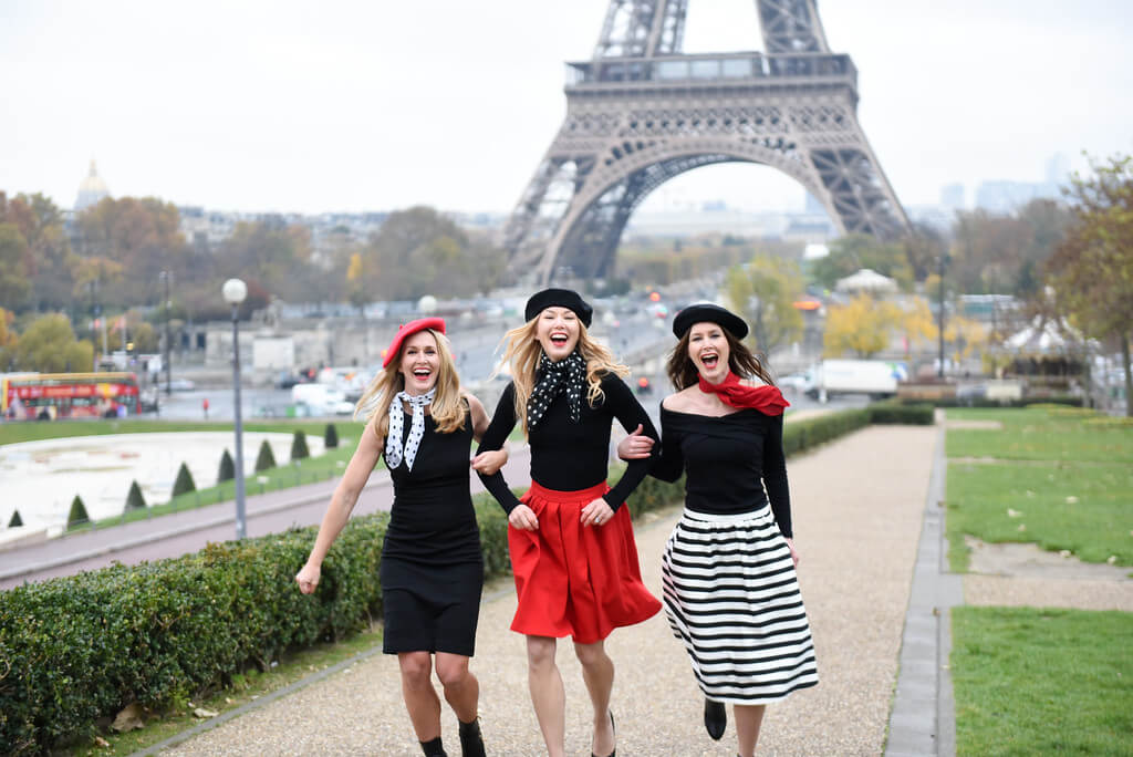 Friends wearing skirts and stripes running in front of Eiffel tower in Paris, France