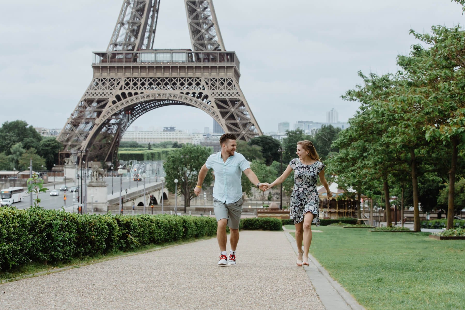 couple holding hands skipping and laughing in front of the Eiffel Tower, Paris, France