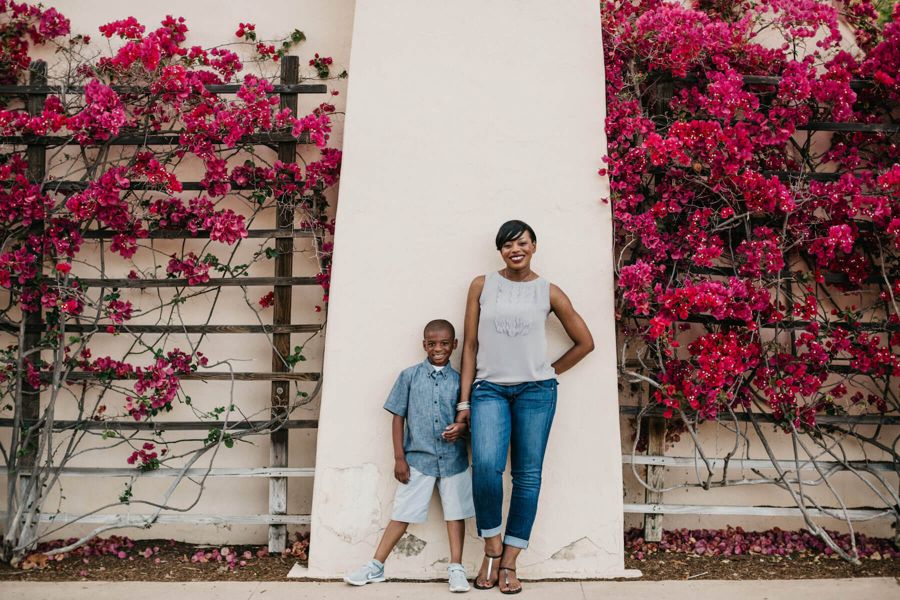 mother and son standing in front a building with flowing flowers, having a good time in San Diego, California