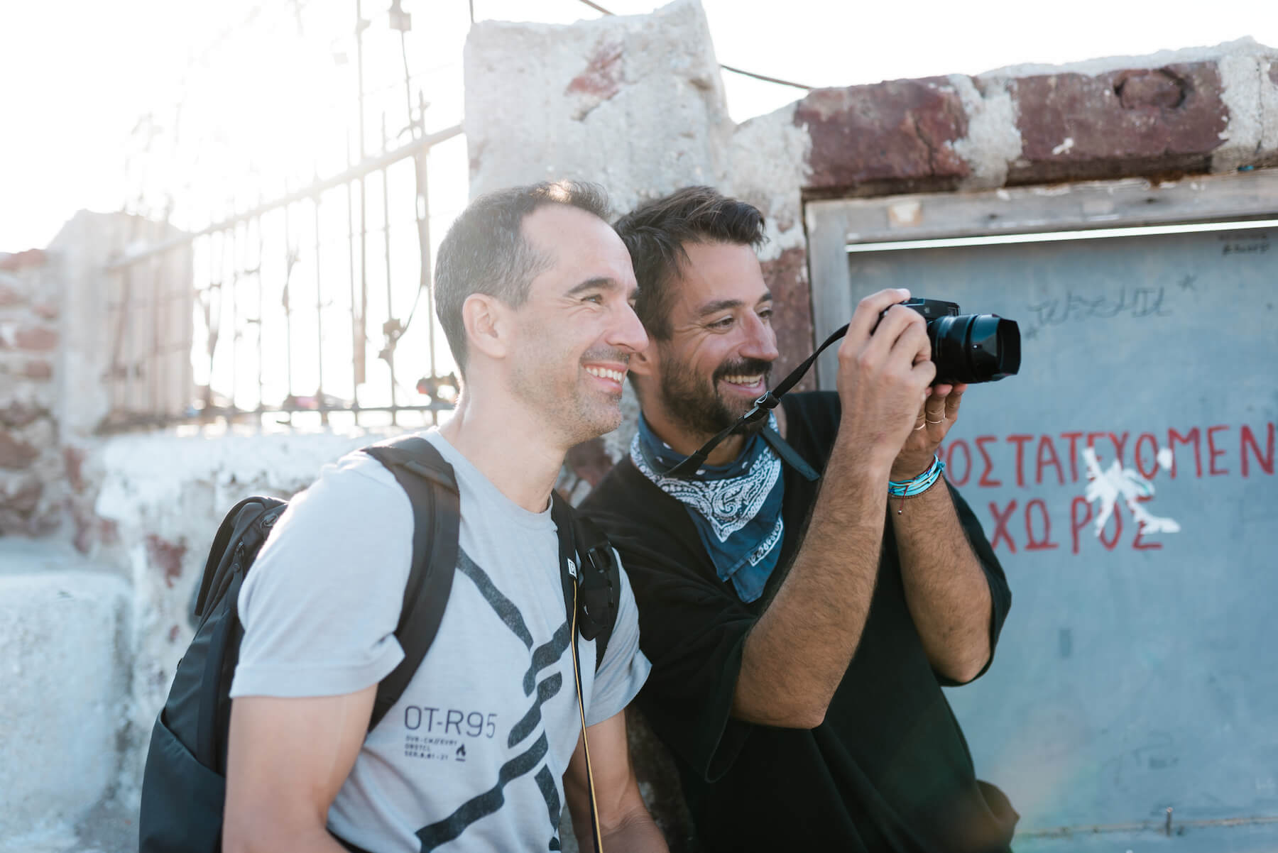 Two photographers shooting and laughing in Santorini, Greece