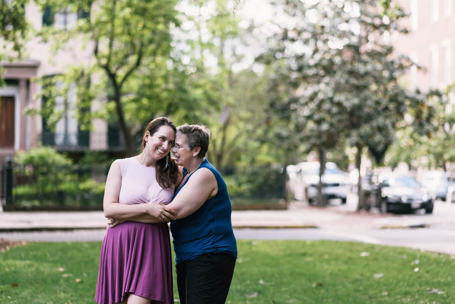 a LGBTQ couple hugging in a park near historic homes in Savannah, Georgia, United States of America