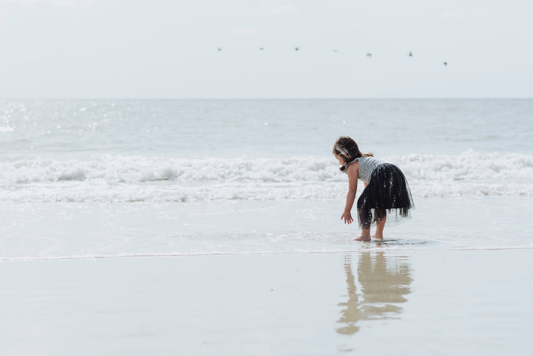 a girl bending over and having fun in the water on a beach in Savannah, Georgia, United States of America