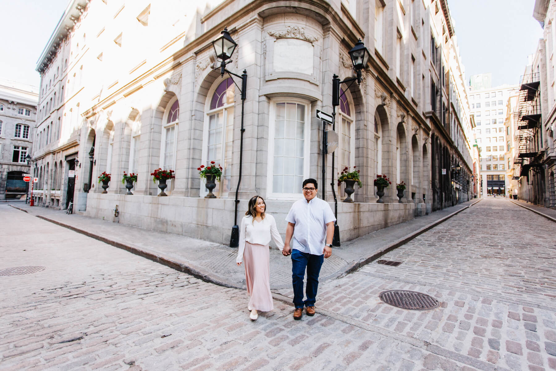 A couple smile in front of a historic building in Old Montreal while on a couple photoshoot with Flytographer.