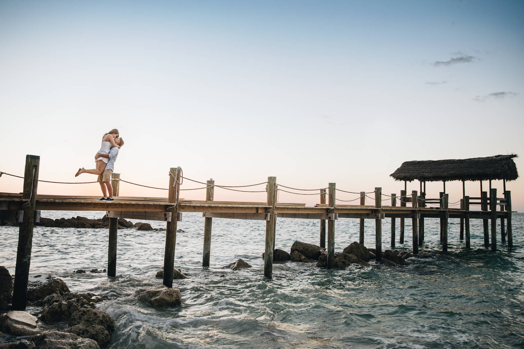 A couple embrace on a dock in Nassau while on a couple photoshoot with Flytographer.