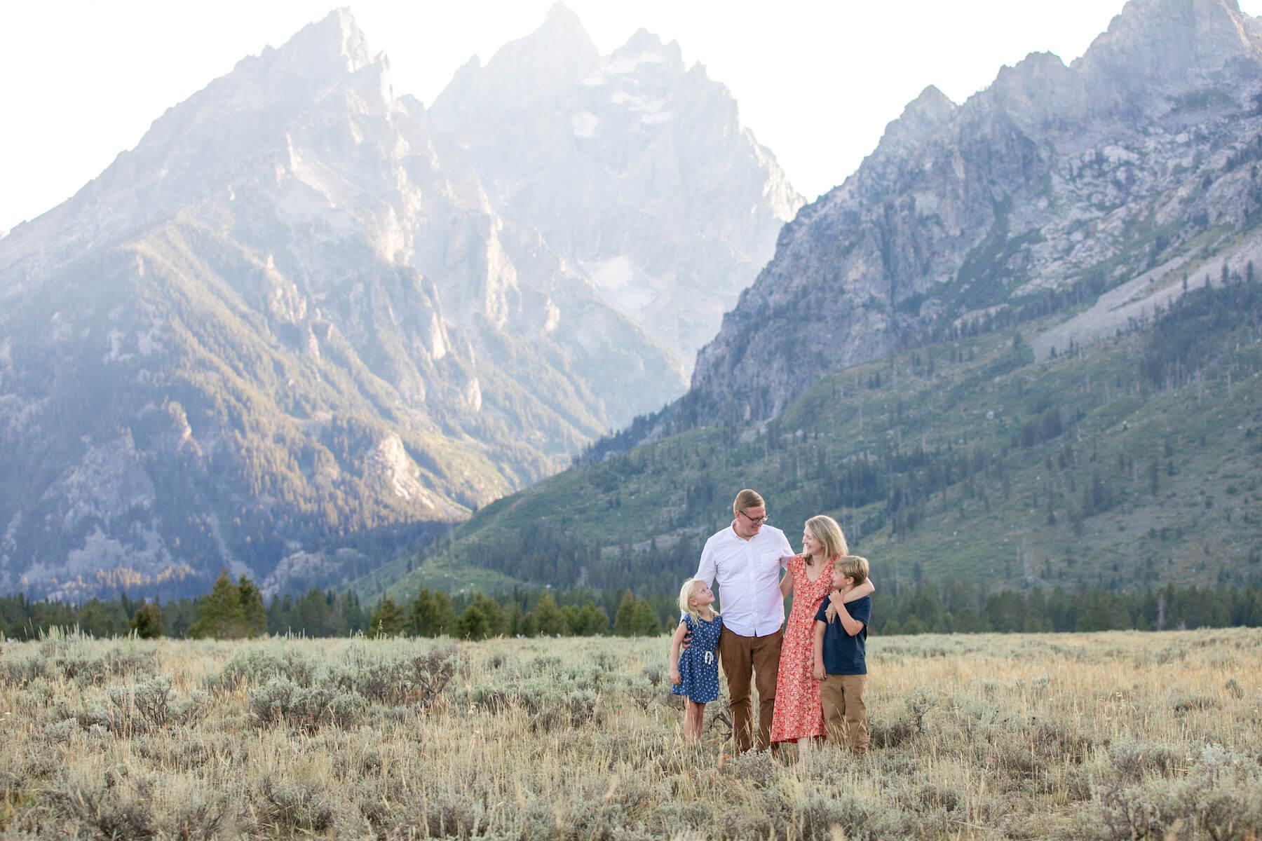 A family walks around with the mountains of Jackson Hole in the background while on a family photoshoot with Flytographer.