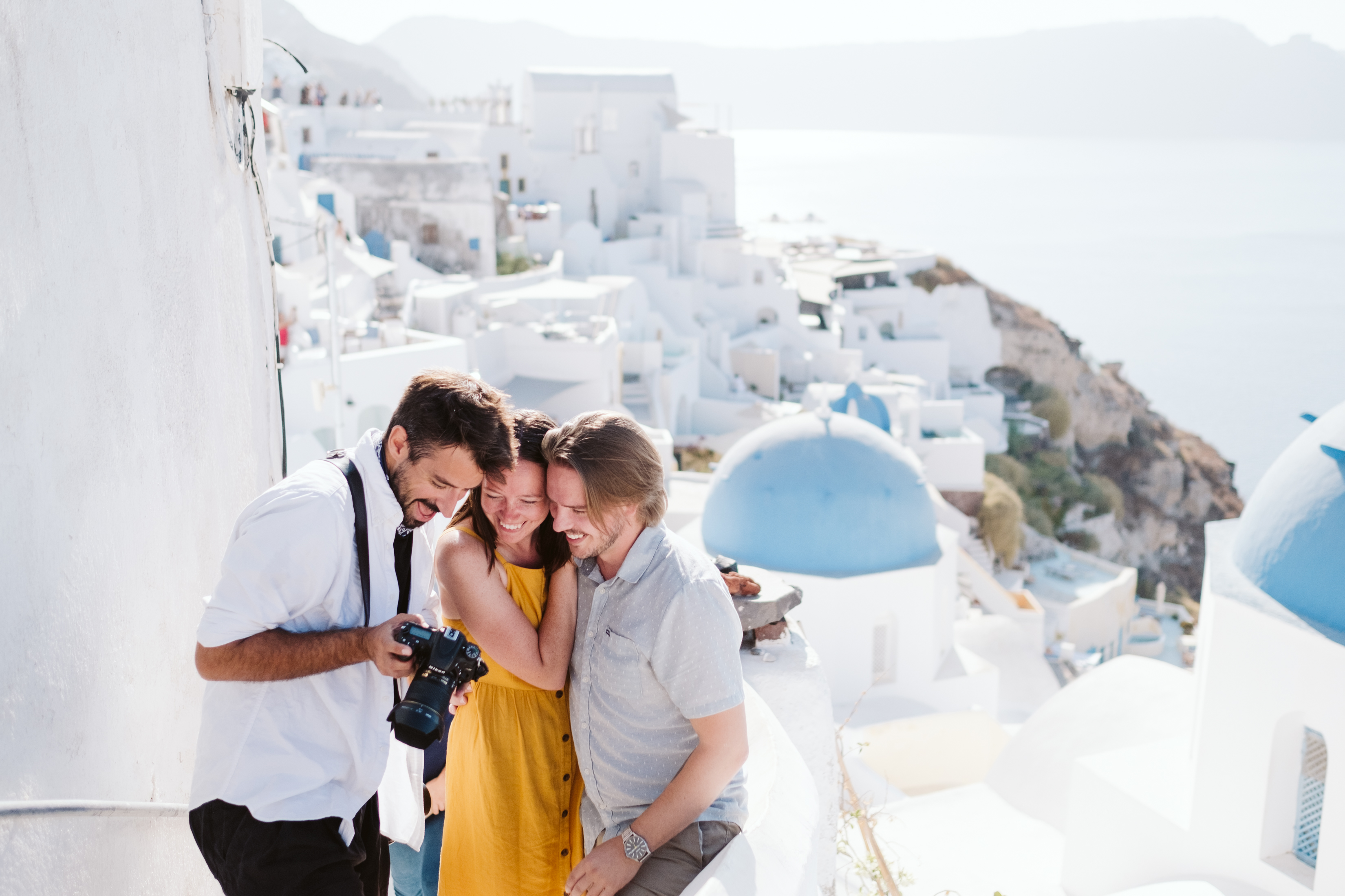 A Flytographer in Santorini showing his shots to a couple on a photoshoot